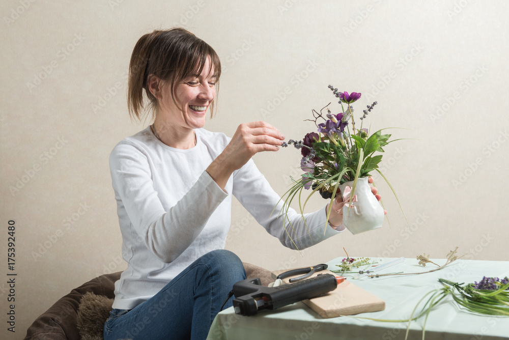 Happy woman during flower decoration process Happy woman during flower decoration process