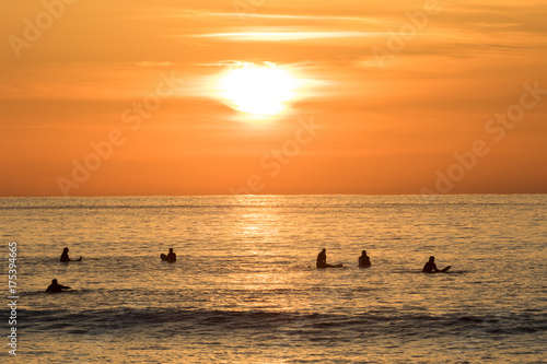 Surfers waiting in the water for the next wave. Sunset at Unstad beach