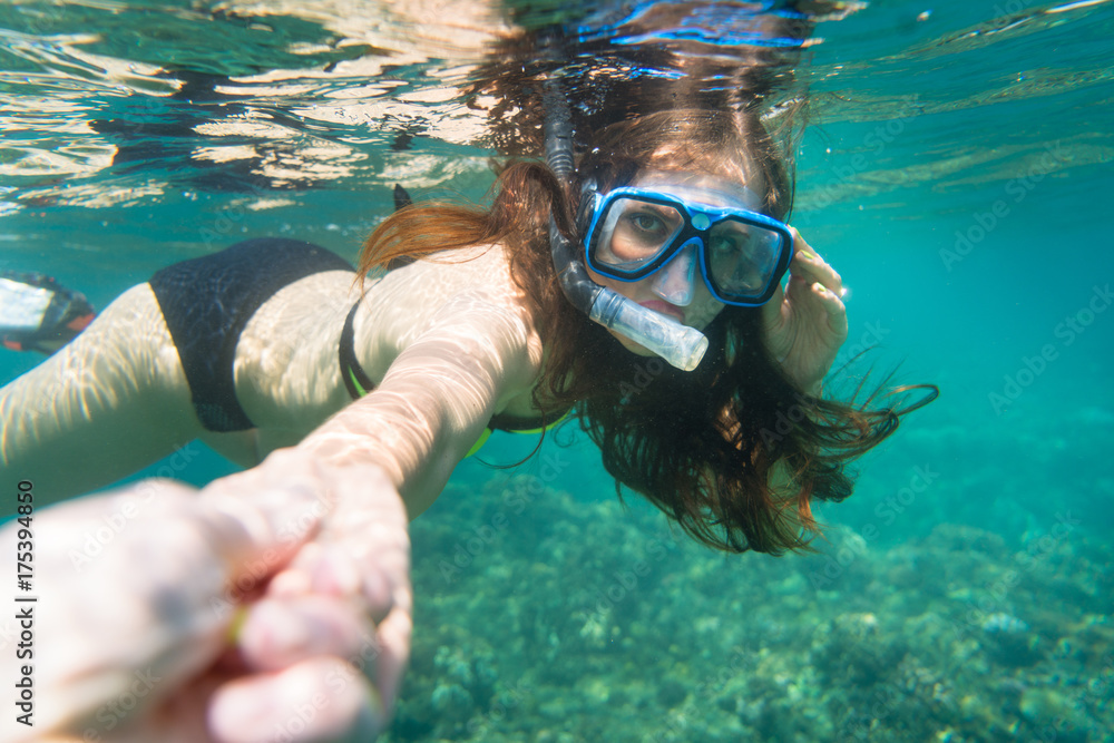 Naklejka premium Snorkelling woman in yellow bikini makes tempting gesture in ocean