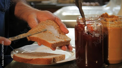 Close up, person makes peanut butter and jelly sandwich