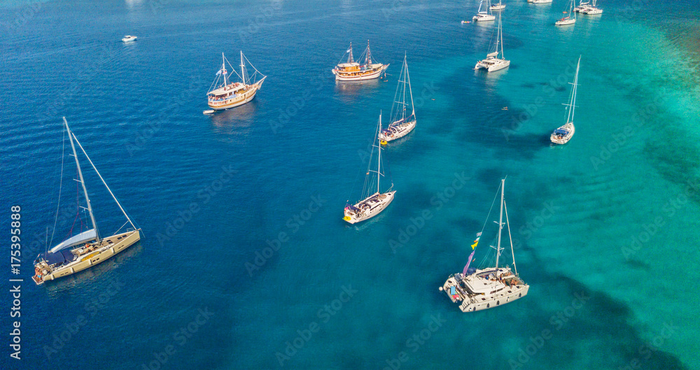 Obraz premium Aerial view of group of sailing boats anchoring on buoys.