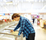 Man shopping in supermarket, reading product information