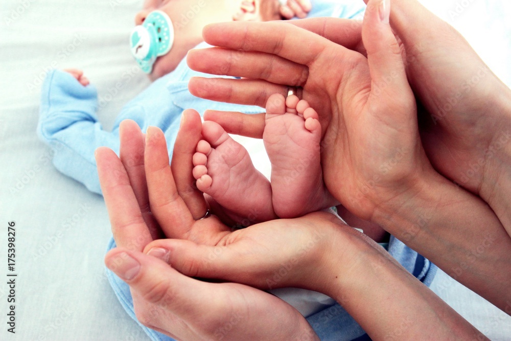 Stopy niemowlęcia otoczone rękami rodziców - obrazy, fototapety, plakaty 