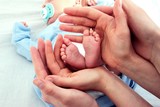 Stopy niemowlęcia otoczone rękami rodziców