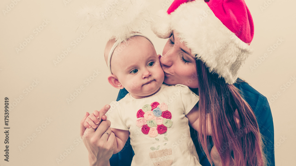 Fototapeta premium Mother wearing santa hat holding baby