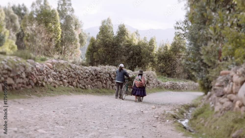 Couple of old Bolivian farmers walking on a dirt path wearing traditional costumes Couple of old Bolivian farmers walking on a dirt path wearing traditional costumes