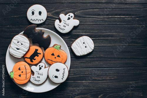 A preparation for Halloween. A plate with scary gingerbreads on a black wooden background.