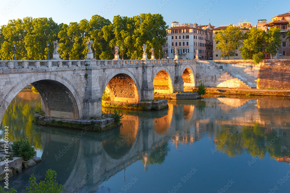 Fototapeta premium Saint Angel bridge with mirror reflection in Tiber River at sunset in Rome, Italy.