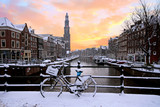 Amsterdam covered with snow with the Westerkerk in winter in the Netherlands at sunset