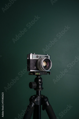 Retro camera on a tripod against green background
