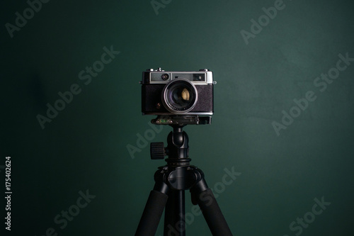 Retro camera on a tripod against green background photo