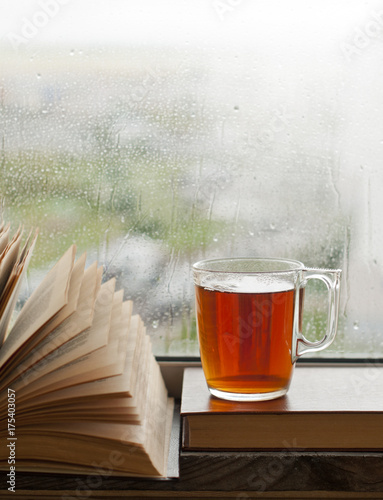 a cup of tea on the window and an open book, autumn rain outside the window, a concept of relaxation