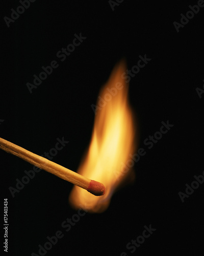 Single burning match on black background