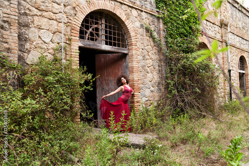Bella ragazza con abito rosso in  un castello abbandonato photo