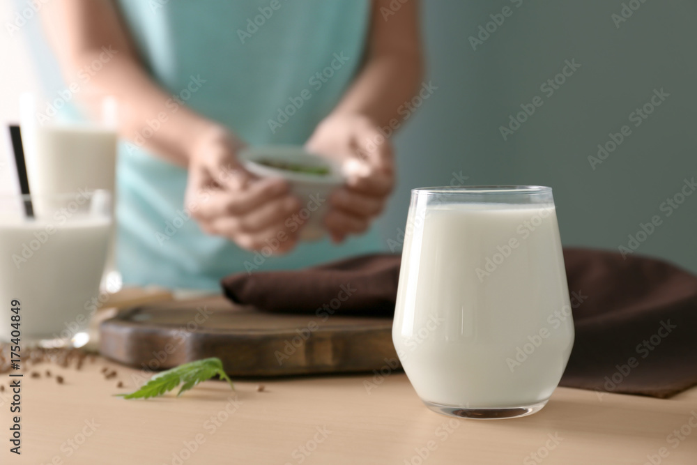 Glass with hemp milk and blurred woman on background Glass with hemp milk and blurred woman on background