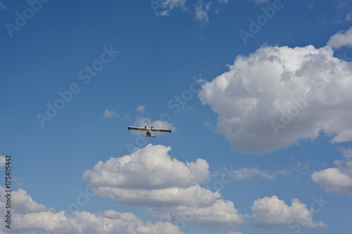 Light airplane against the blue sky with white clouds background