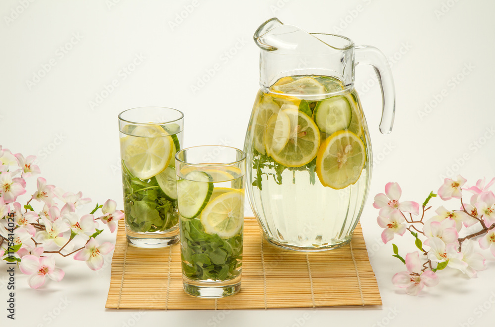 Fototapeta premium refreshing drink with lemon and seasonings in the summer morning with flowers
