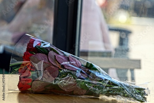 букет из красных роз в упаковке на столе