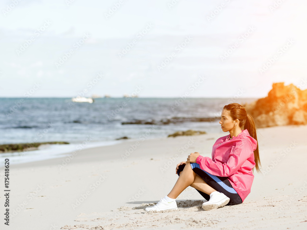 Young woman sitting at the beach in sportswear Young woman sitting at the beach in sportswear