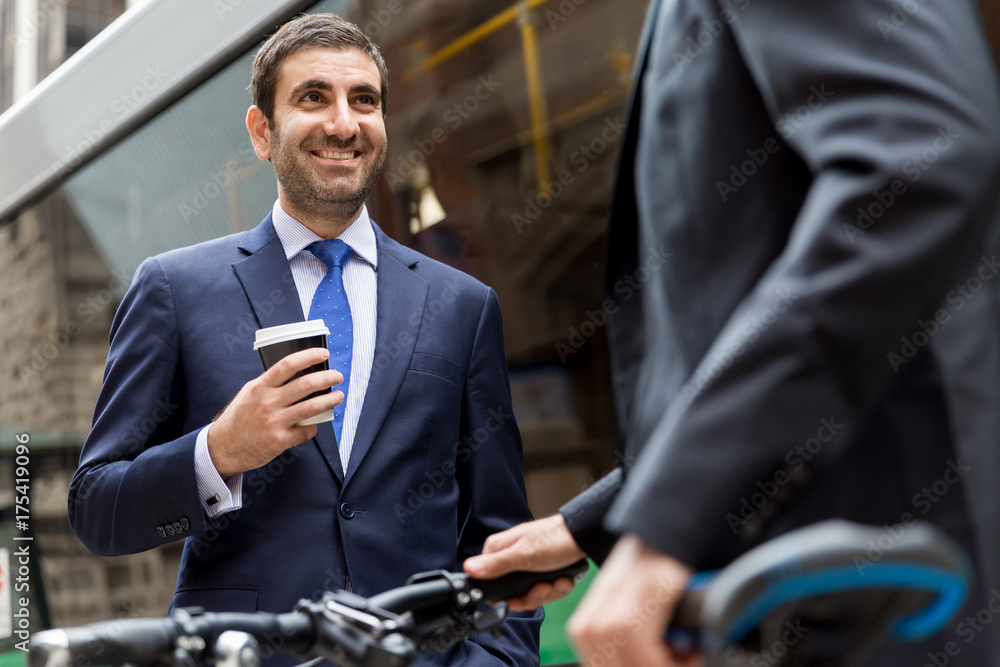 Two young businessmen with a bike in city centre