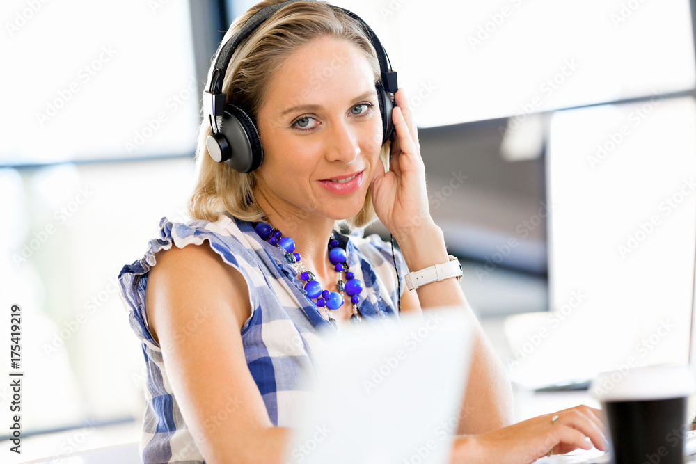 Naklejka premium Young woman in the office with headphones