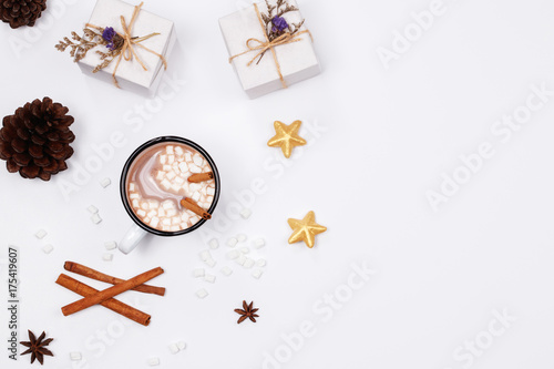 Winter christmas holiday background. Cup of hot chocolate drink with marshmallows, cinnamon sticks, anise star, gift box and golden ornaments on white background.