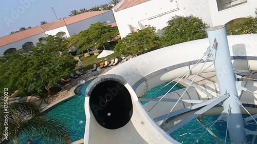 POV of a man riding water slide tube tunnel in water park in slow motion. Waterslides in aquaparks are pleasant and popular pastime recreational sites. photo