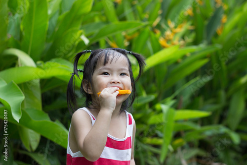 Cute child girl portrait eating oranges Outdoor .