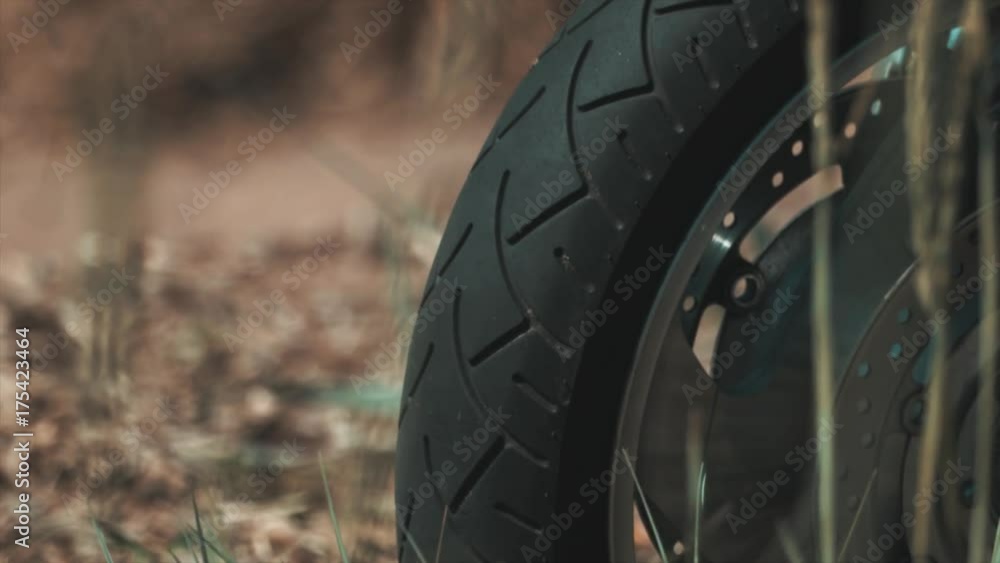 Motorcycle wheel rubber tire on dirt road, grass shakes in wind, sunny summer day, close up shot Motorcycle wheel rubber tire on dirt road, grass shakes in wind, sunny summer day, close up shot