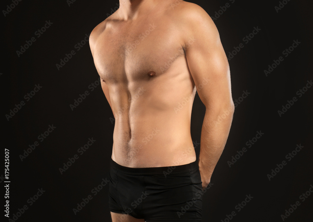 Young man in underwear on black background