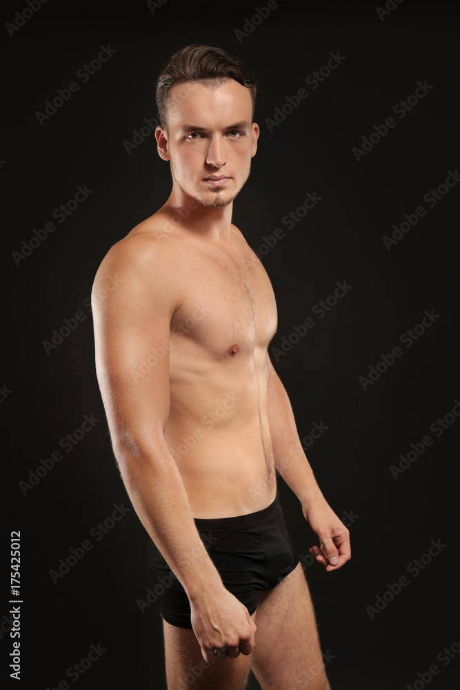 Young man in underwear on black background