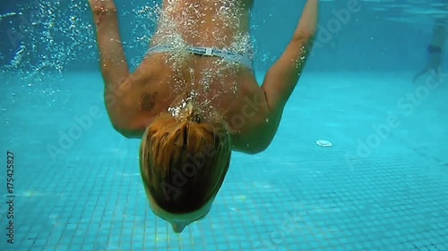 Beautiful woman is diving underwater in swimming pool. Fun and cute recreation slow motion shot of woman with a good figure.