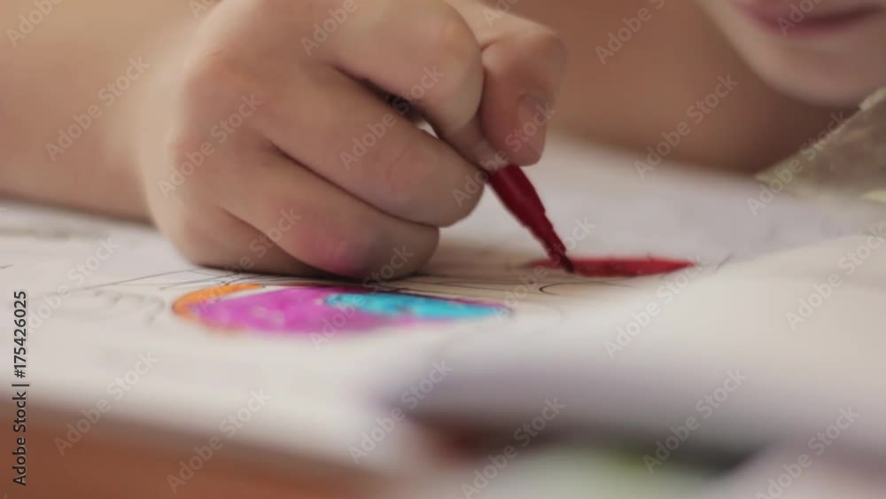 Close-up kid hands with pencil. child draws with colored pencil on paper.