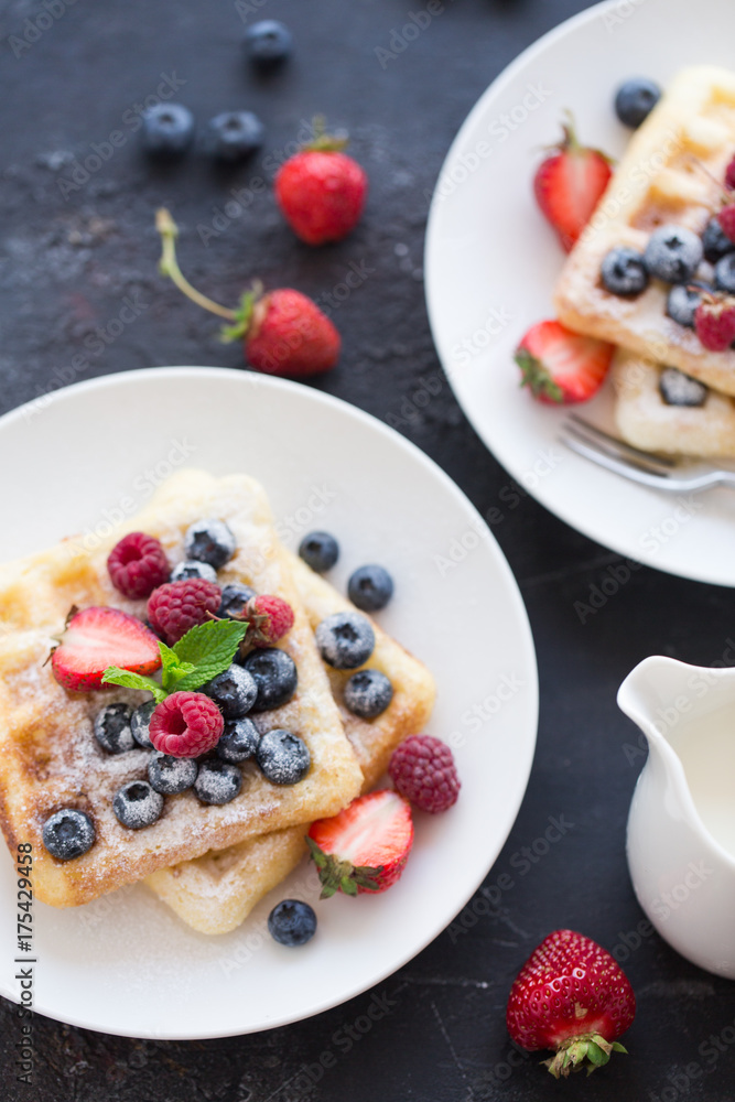 Delicious Belgian waffles with mint leaf and berries on dark background with copy space Delicious Belgian waffles with mint leaf and berries on dark background with copy space