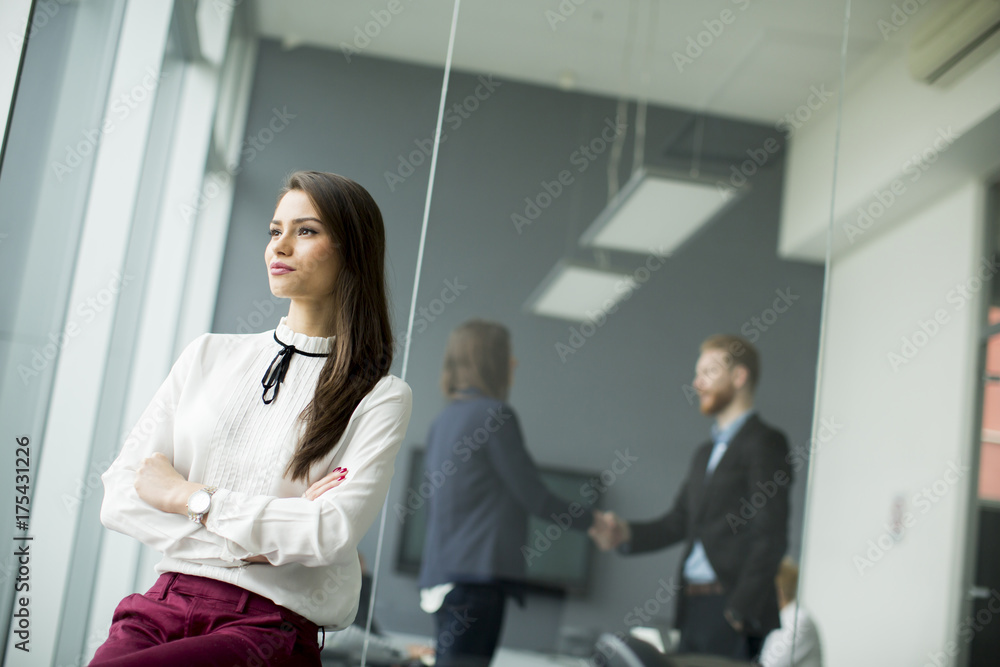 Modern businesswoman standing in modern office with young business people in the background