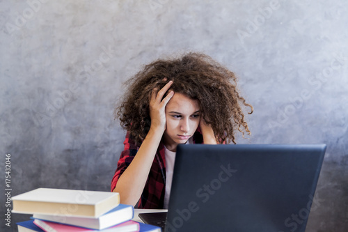 Photos Unhappy teenage girl using laptop at h ome