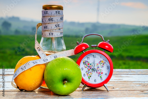 Fresh organic honey in glass jar , measuring tape, green epal , lemon and alarm clock  on old wooden with blurred background , healthy nutrition, strengthening immunity, diet and treatment of flu photo