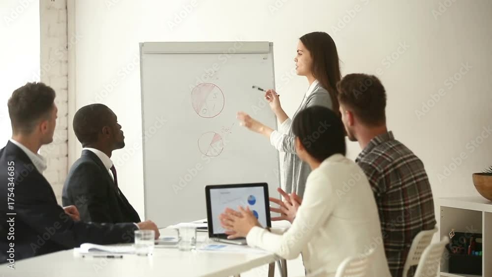 Young businesswoman giving presentation to multi-ethnic mixed group, business coach explaining project charts disagreeing with audience, team leader discussing marketing statistics with employees Young businesswoman giving presentation to multi-ethnic mixed group, business coach explaining project charts disagreeing with audience, team leader discussing marketing statistics with employees