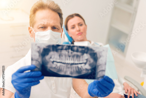 Serious mature doctor examining x ray jaws scan