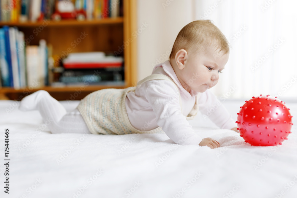 Cute baby playing with red gum ball, crawling, grabbing