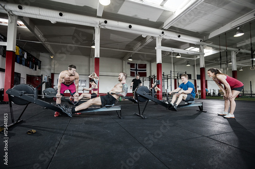 Instructors Motivating Clients Exercising In Gym