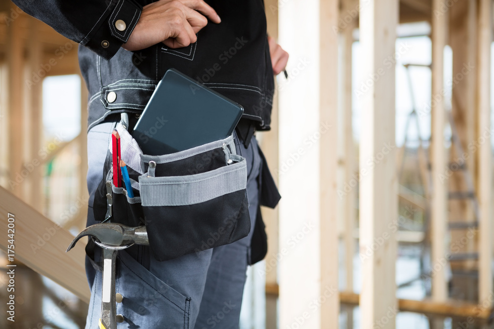 Carpenter With Digital Tablet And Tools In Bag At Site