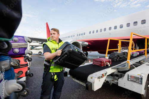 Worker Stacking Bags On Trailer At Runway photo