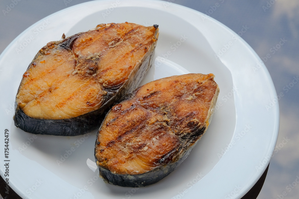 A grilled mackerel fish on white plate is a one of the Malaysian people favorite dish A grilled mackerel fish on white plate is a one of the Malaysian people favorite dish