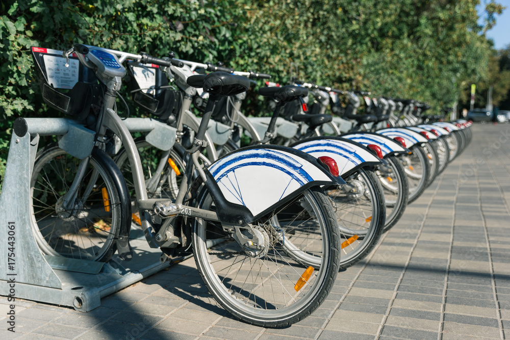 Set of vacant public bikes orderly parking locked on rack available for rental.