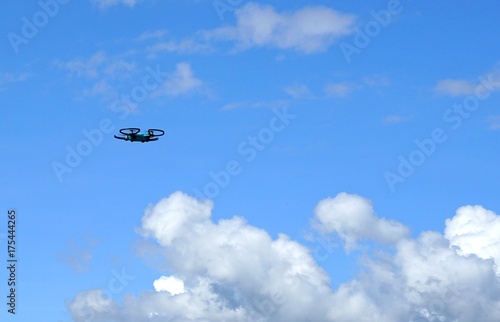 Drone ( Unmanned Aerial Vehicle) hovering in blue sky with white clouds background