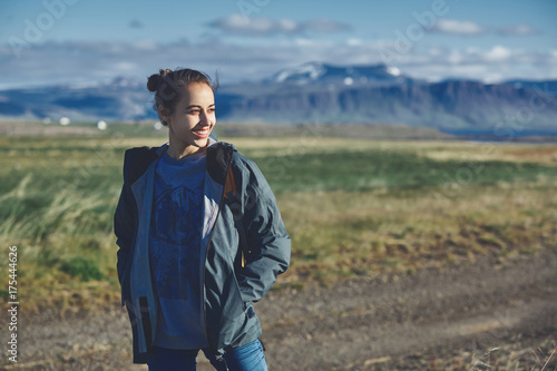 Girl in warm clothing observing surroundings on background of mountains of Iceland. © vitaliymateha