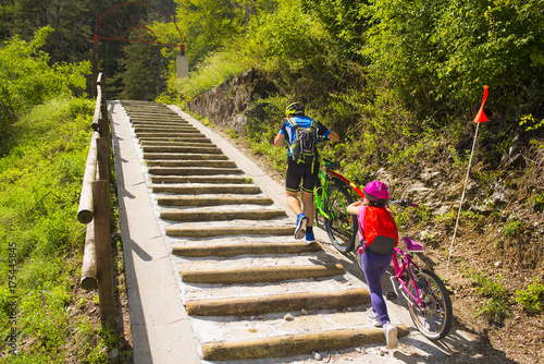 Father and daughter climb the steps with bicycle