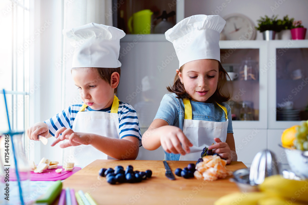 Kid chefs in the kitchen preparing a healthy fruit snack Kid chefs in the kitchen preparing a healthy fruit snack