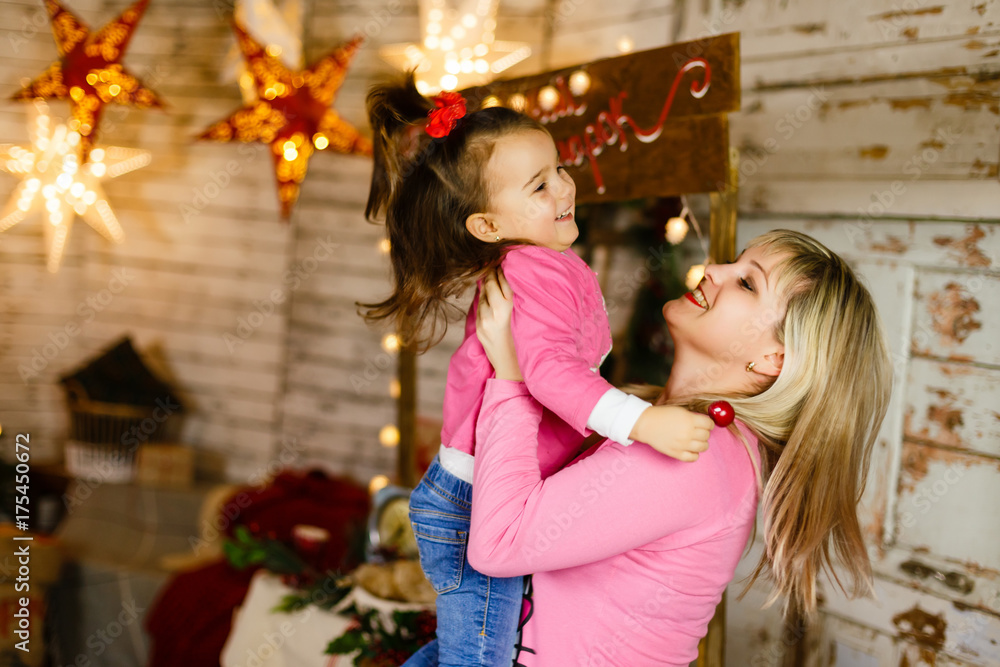 happy mother with her daughter playing near the Christmas tree happy mother with her daughter playing near the Christmas tree
